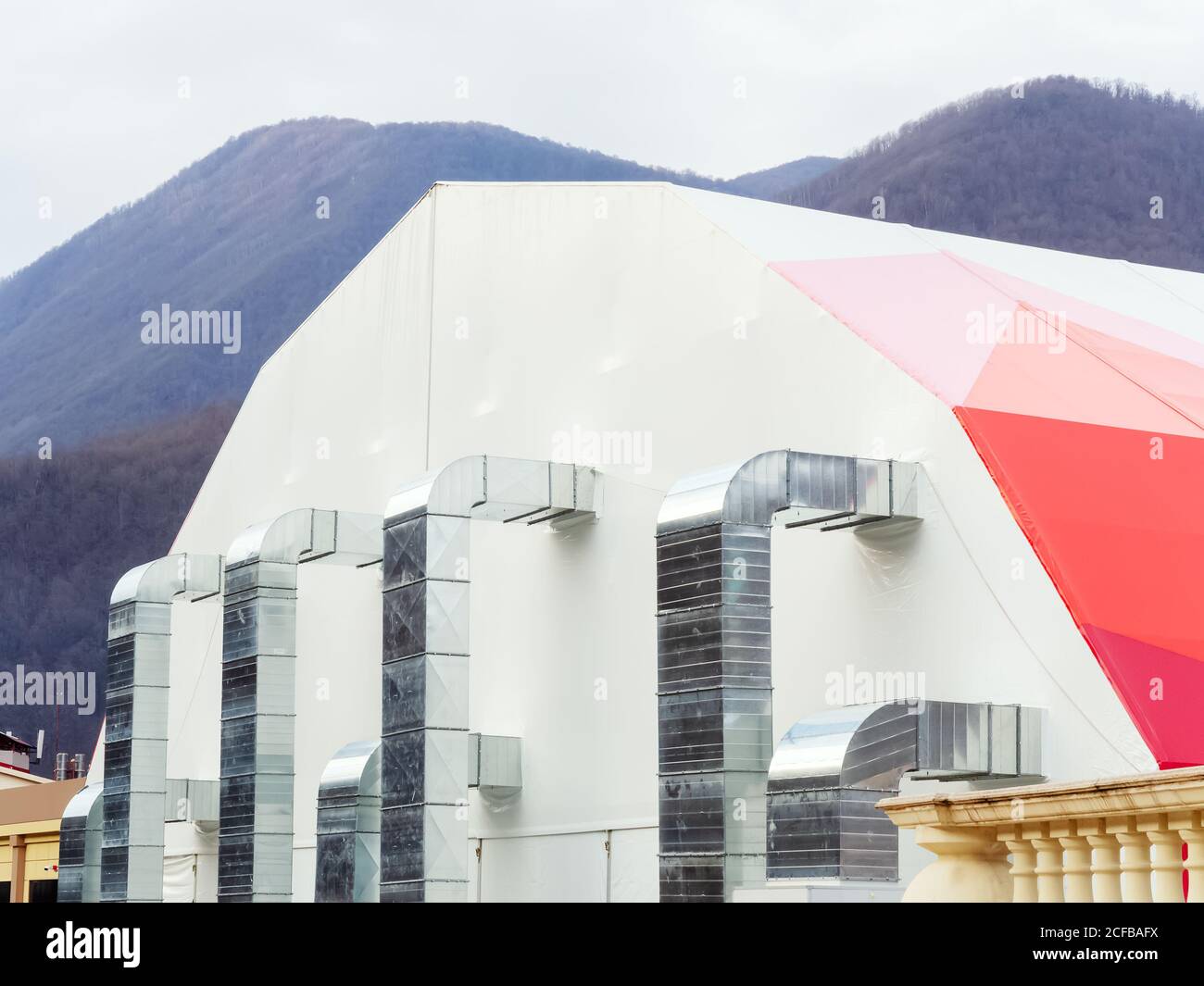Grand bâtiment de tente avec des tuyaux métalliques sur le mur contre la toile de fond des montagnes Banque D'Images