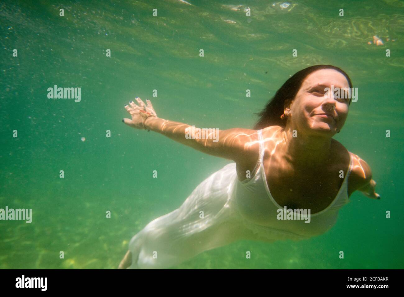 Une femme en robe danse et plonge sous le mer Banque D'Images
