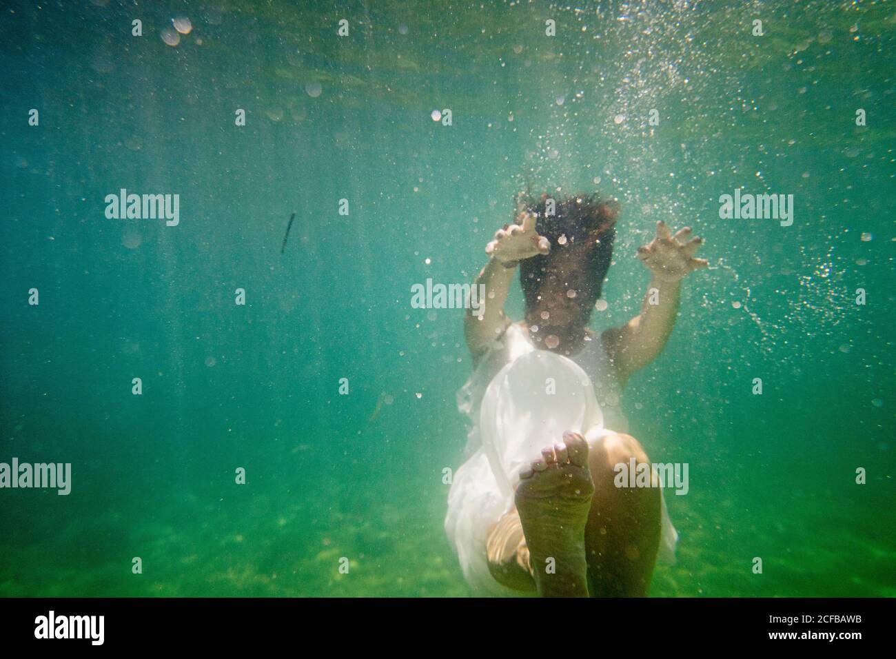 Une femme en robe danse et plonge sous le mer Banque D'Images