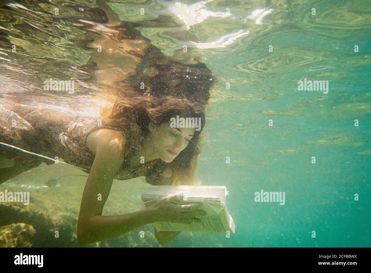 Une femme lit un livre sous la mer Banque D'Images