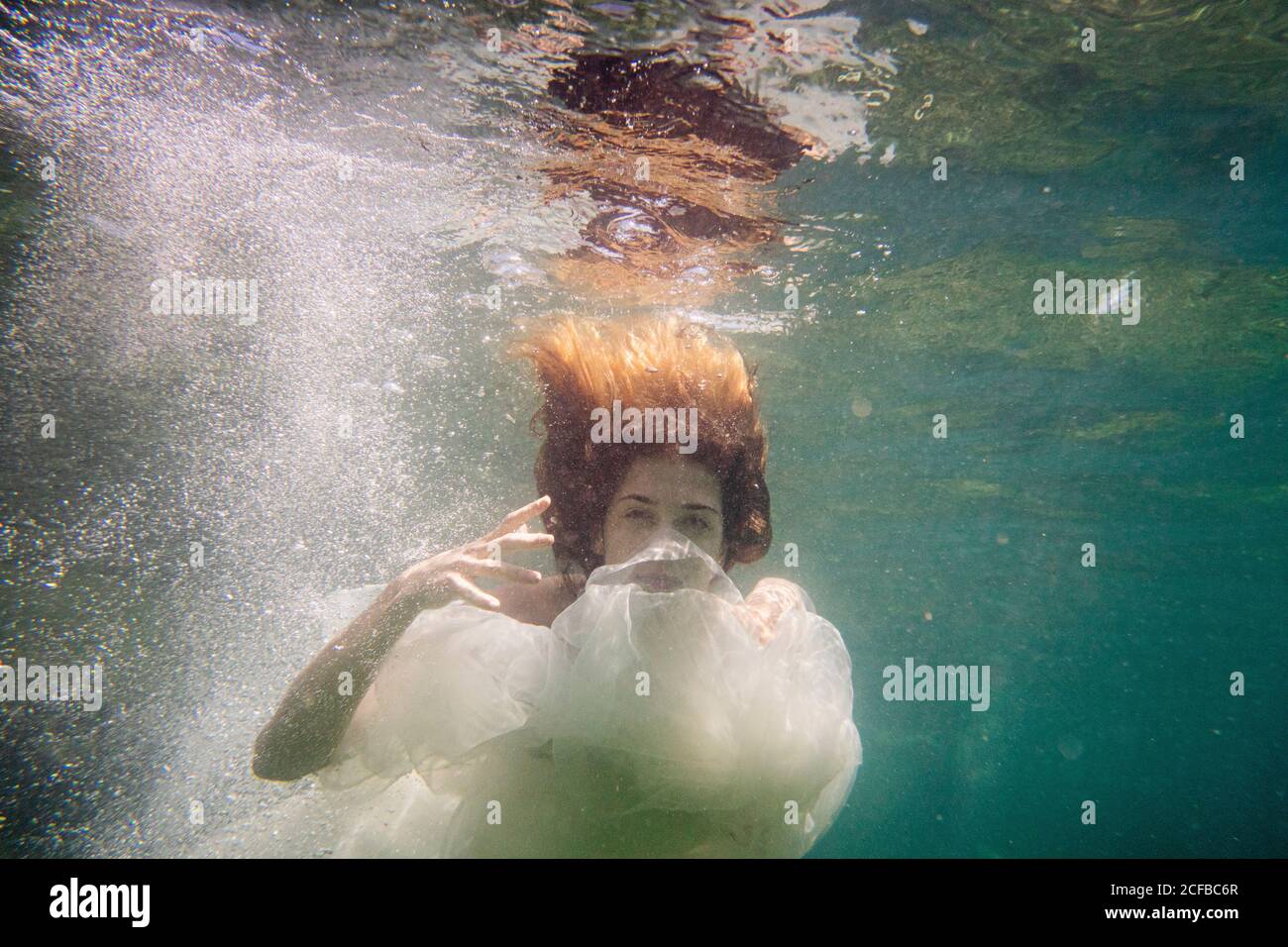 Une femme nue danse et plonge avec des tissus transparents sous la mer Banque D'Images