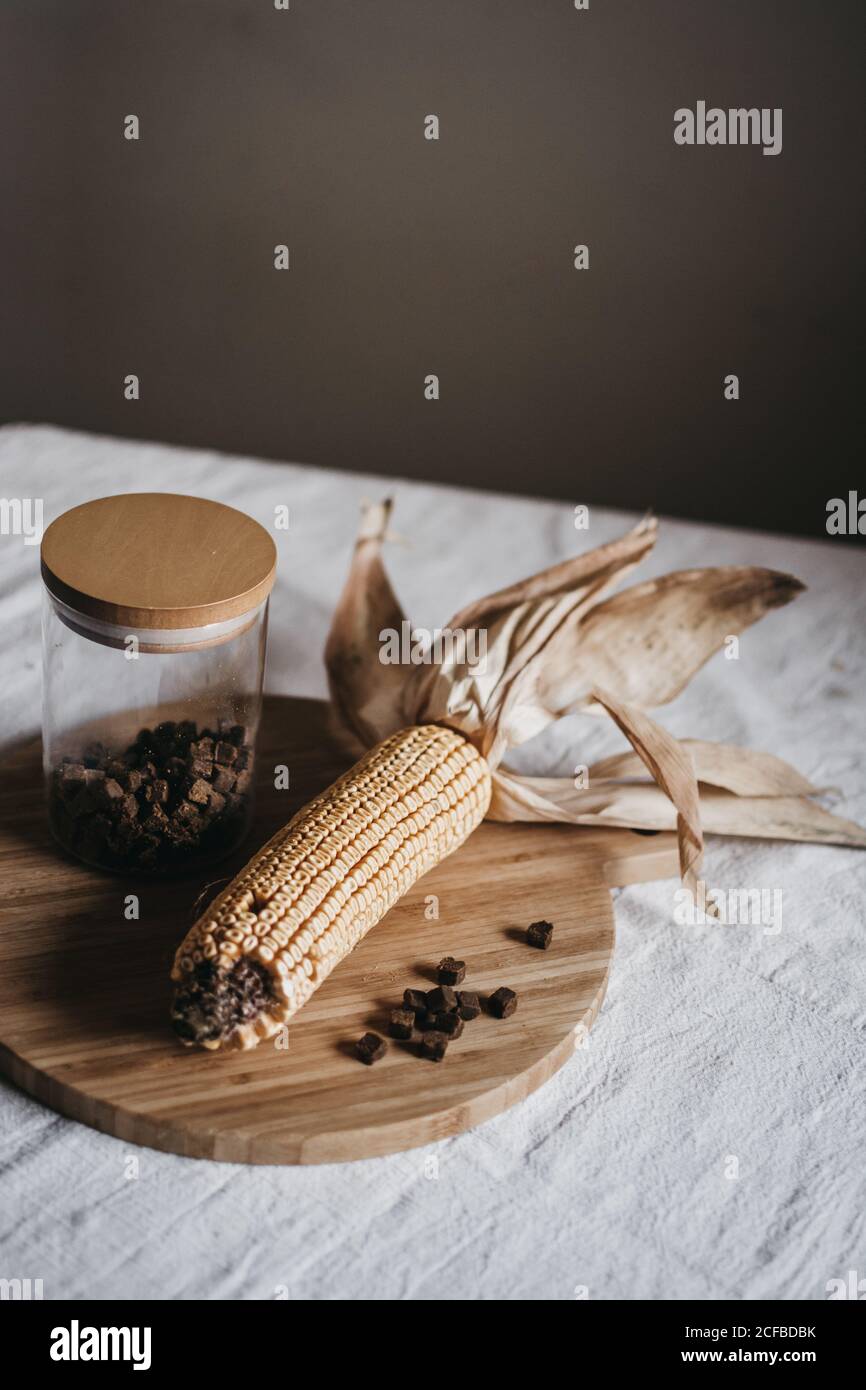 Maïs séché sur l'épi placé sur le panneau de bois près du pot avec des épices brunes sur la table de cuisine Banque D'Images