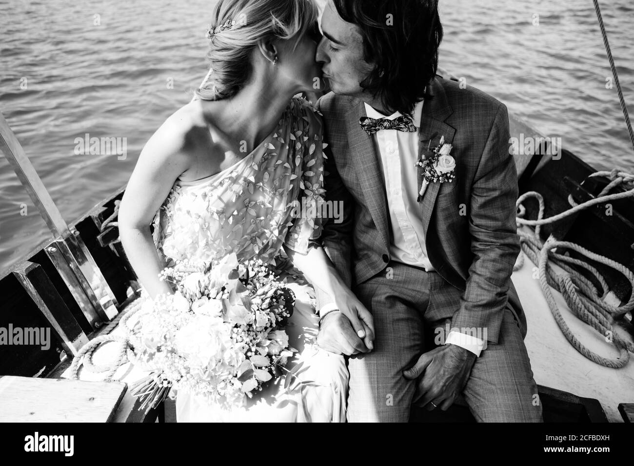 Les amoureux mariés satisfaits de vêtements de mariage embrassant tout en se relaxant bateau avec mer sur fond Banque D'Images