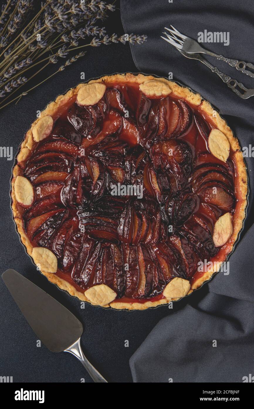 Tarte maison avec pruneaux placés sur fond sombre. Tarte aux prunes. Vue de dessus, plan d'appartement. Banque D'Images
