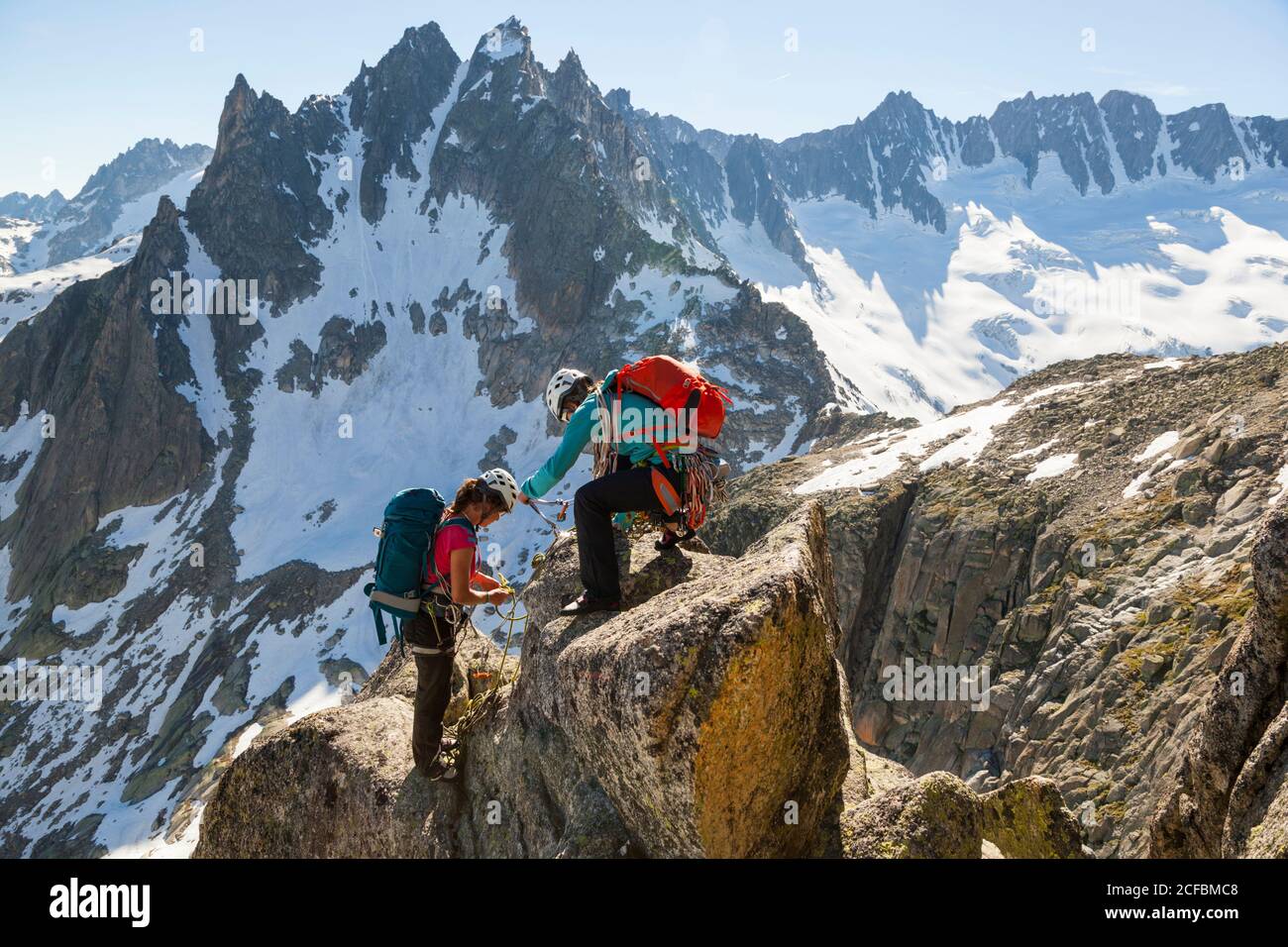 Les femmes se préparent à descendre du sommet de la via Amici (5c) sur la route d'escalade de Lochberg, col de Furka, Uri, Suisse. Banque D'Images