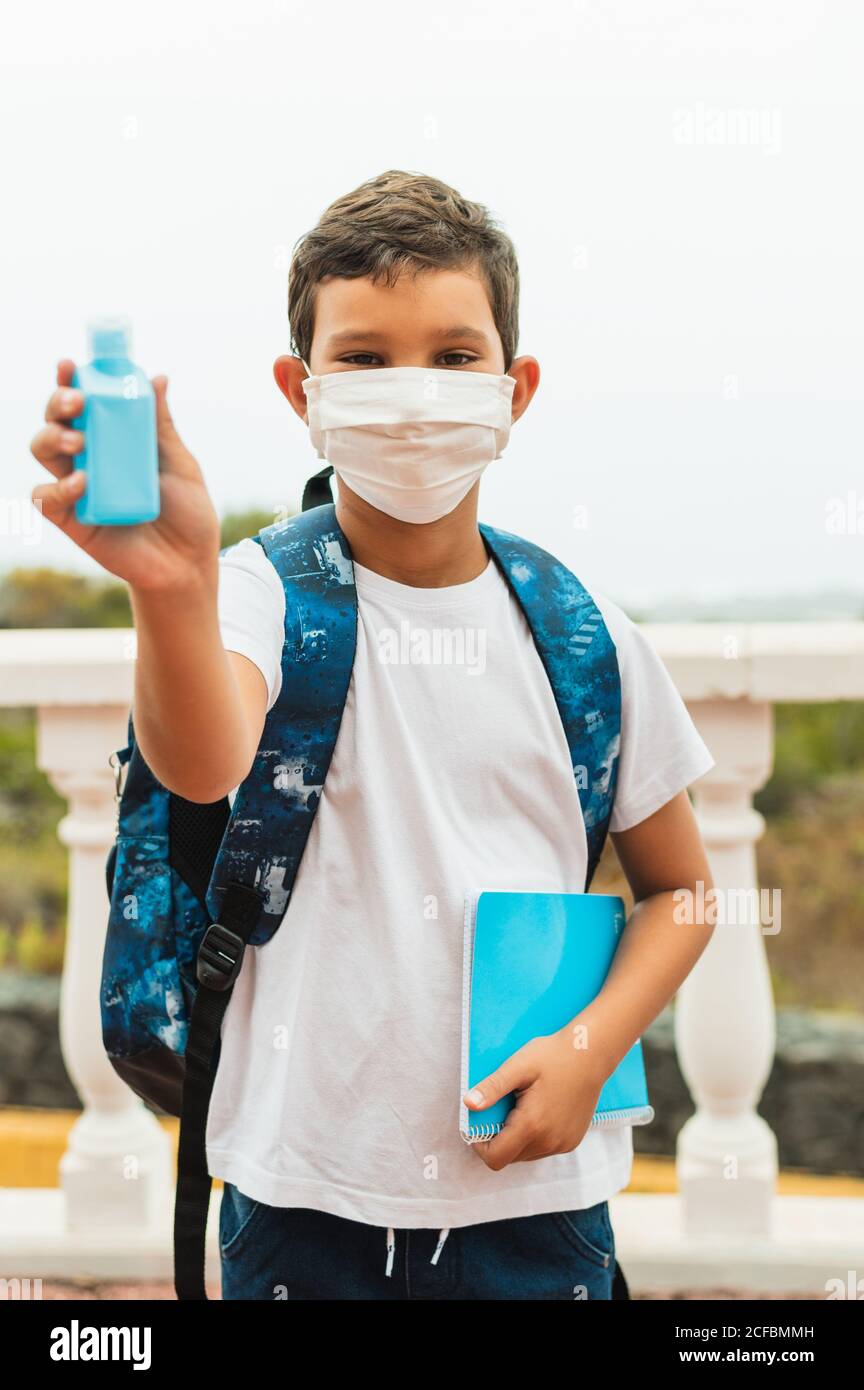 Garçon étudiant avec masque facial appliquant de l'alcool pour les mains gel. Rouvrir l'école à partir de la fermeture. Retour à l'école : pandémie du coronavirus Covid-19. Nouveau lifest normal Banque D'Images