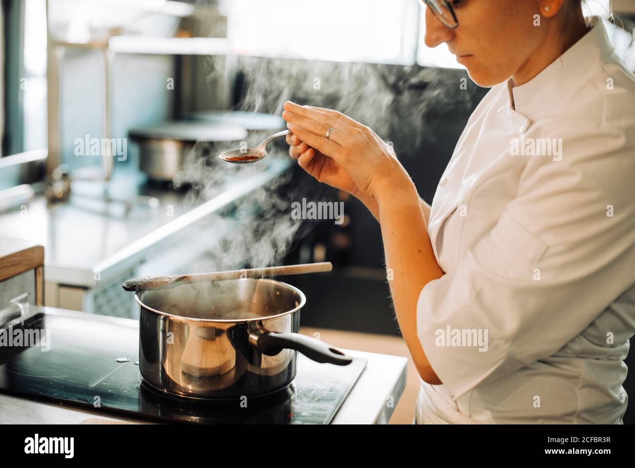 Une femme chef assaisonnement des plats chauds tout en se tenant à la  cuisinière Photo Stock - Alamy