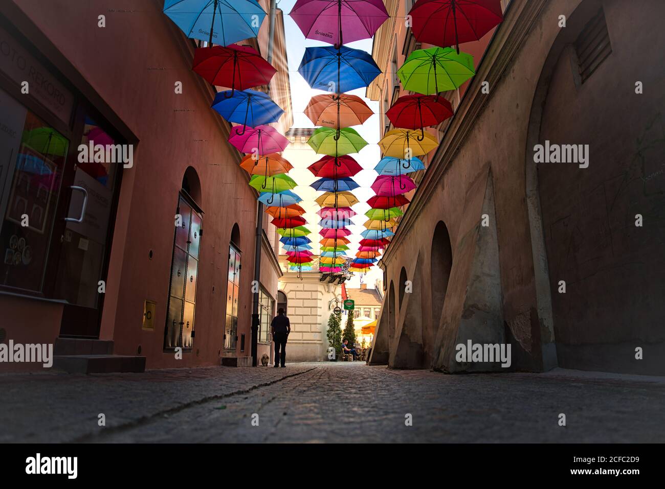 Tarnow, juin 2020: Parasols colorés d'été suspendus entre les bâtiments de la vieille ville. Ciel de parasols colorés avec des rayons du soleil. Rue décorée Banque D'Images