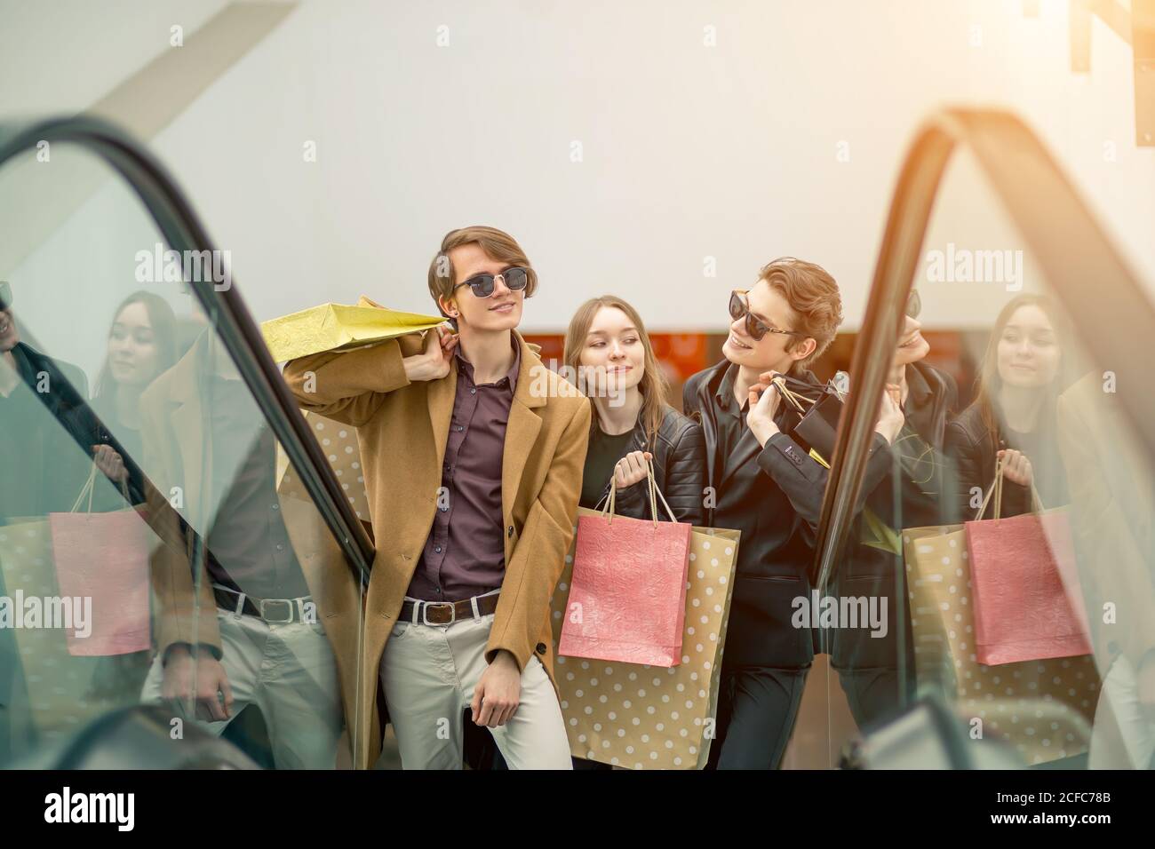 Trois copines sur escalator with shopping bags Banque D'Images