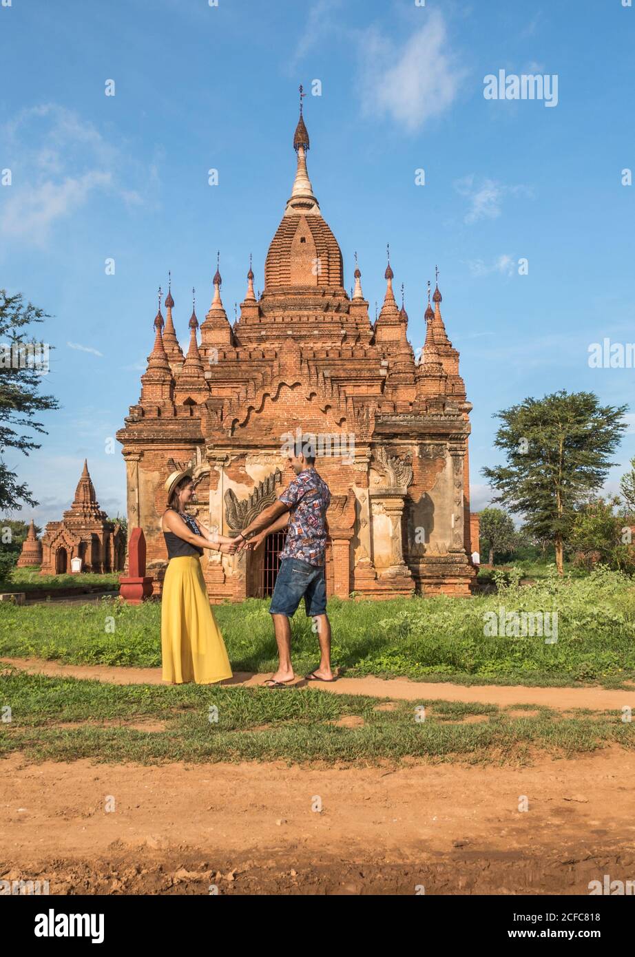 Vue latérale d'un jeune couple heureux amoureux tenant les mains Tout en se tenant à côté du magnifique temple ancien de Bagan Myanmar en journée ensoleillée et en vacances d'été Banque D'Images