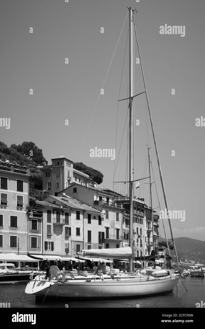 Vue sur le port de Portofino avec un voilier. Portofino est un complexe de luxe situé sur la riviera italienne, en Ligurie, en Italie. Photographie en noir et blanc Banque D'Images