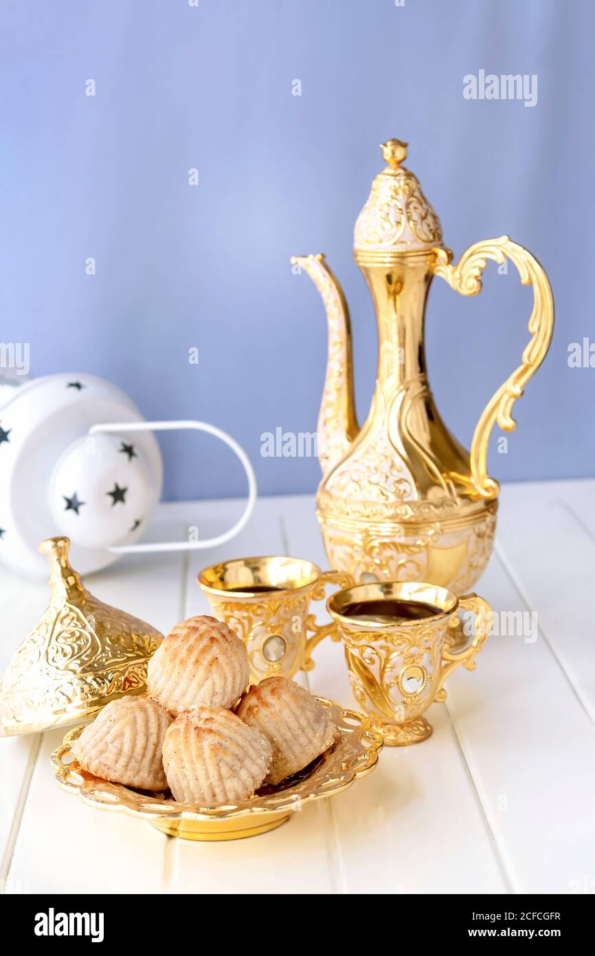 Concept de Ramadan. Maamoul pâte traditionnelle arabe fourrée ou biscuit avec des dattes ou des noix servi avec un ensemble de café doré. Bonbons de l'est. Gros plan. Blanc WO Banque D'Images