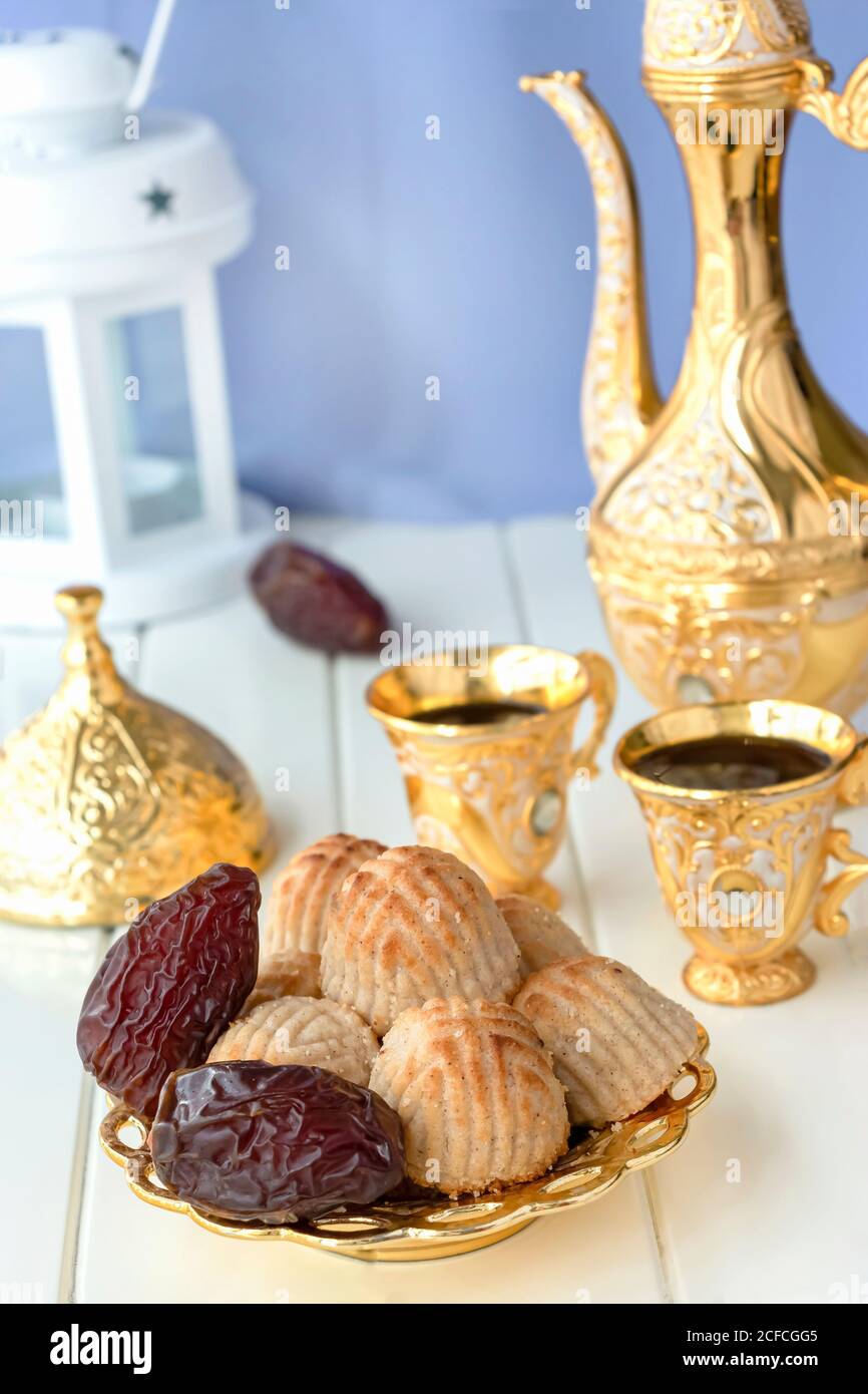 Concept de Ramadan. Maamoul pâte traditionnelle arabe fourrée ou biscuit avec des dattes ou des noix servi avec un ensemble de café doré. Bonbons de l'est. Gros plan. Blanc WO Banque D'Images