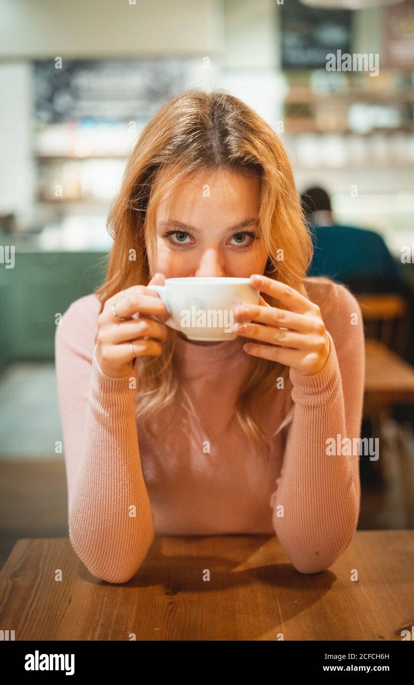 Jeune femme ayant une tasse de café à table dans le café Banque D'Images