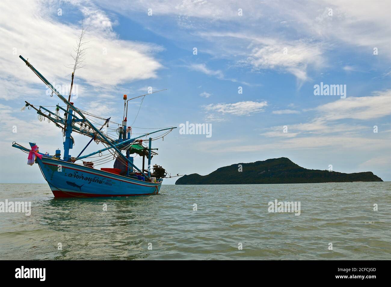 Un bateau de pêche traditionnel en bois amarré à marée haute avec une petite île déserte en arrière-plan. Banque D'Images