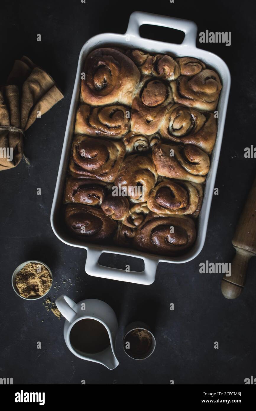 De dessus plateau avec des petits pains à la cannelle maison frais et du bois goupille élastique sur un panneau en marbre blanc Banque D'Images