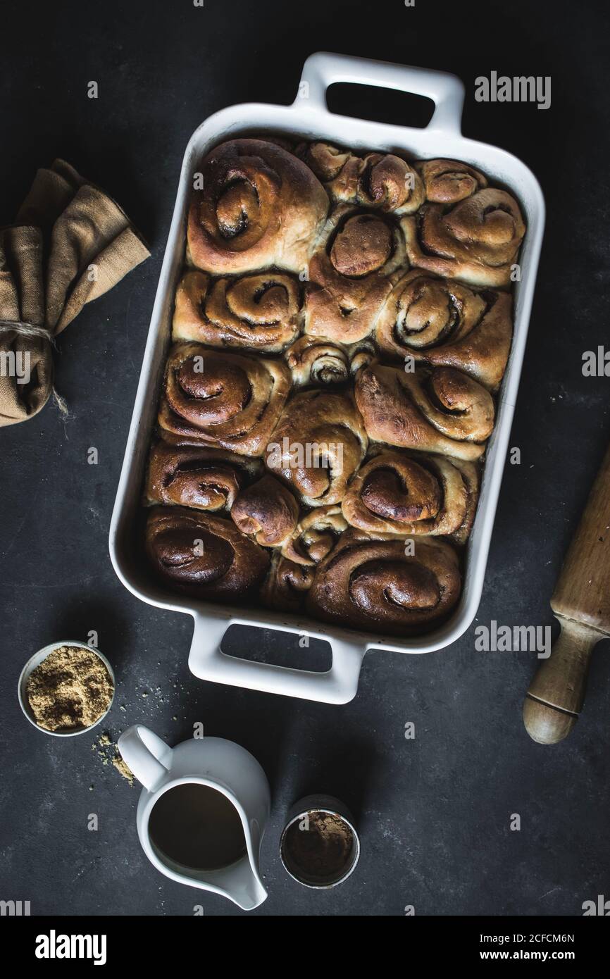 De dessus plateau avec des petits pains à la cannelle maison frais et du bois goupille élastique sur un panneau en marbre blanc Banque D'Images