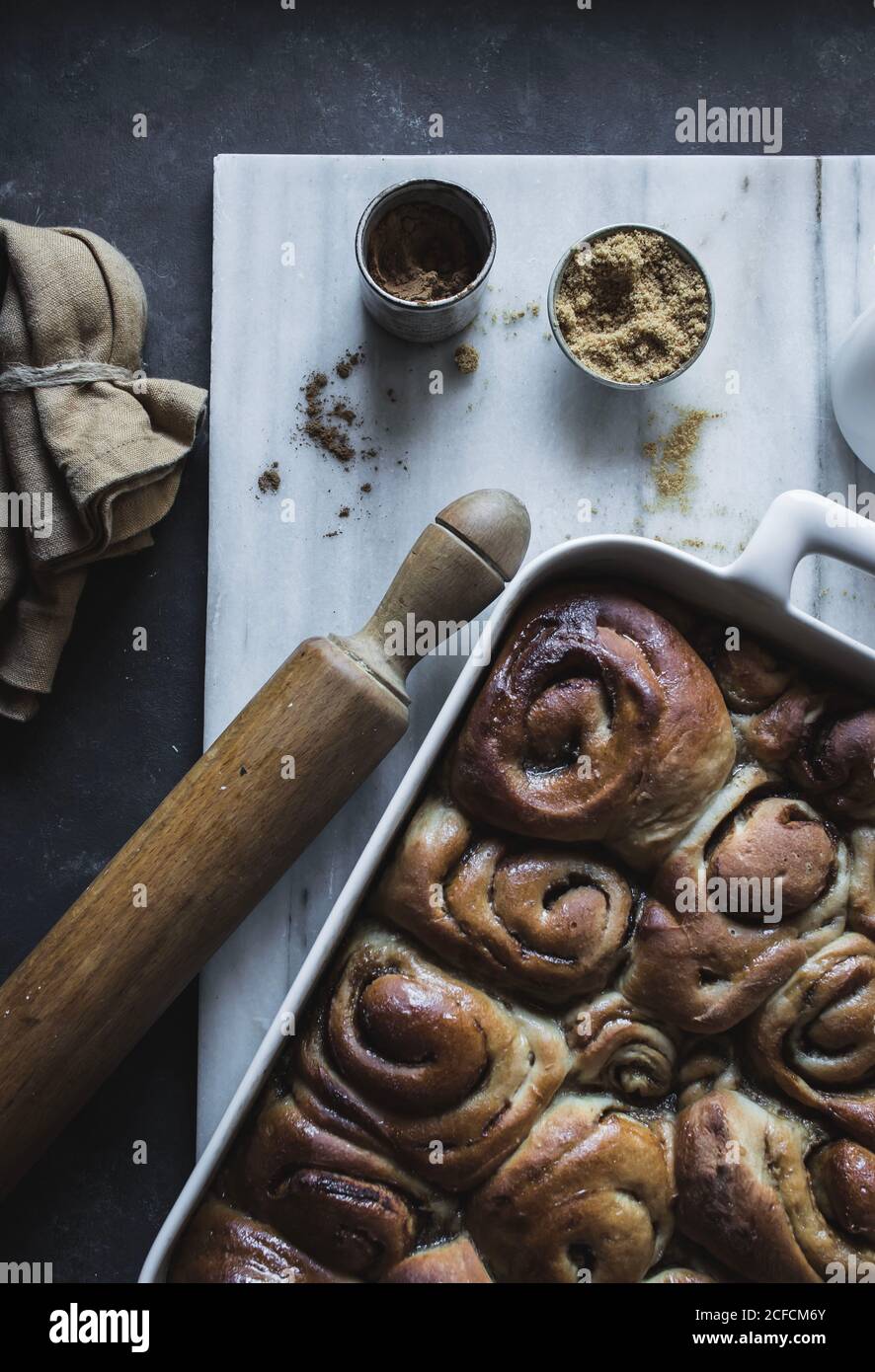 De dessus plateau avec des petits pains à la cannelle maison frais et du bois goupille élastique sur un panneau en marbre blanc Banque D'Images