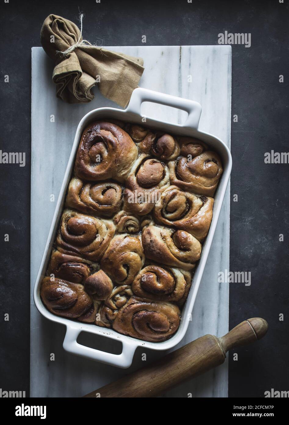 De dessus plateau avec des petits pains à la cannelle maison frais et du bois goupille élastique sur un panneau en marbre blanc Banque D'Images