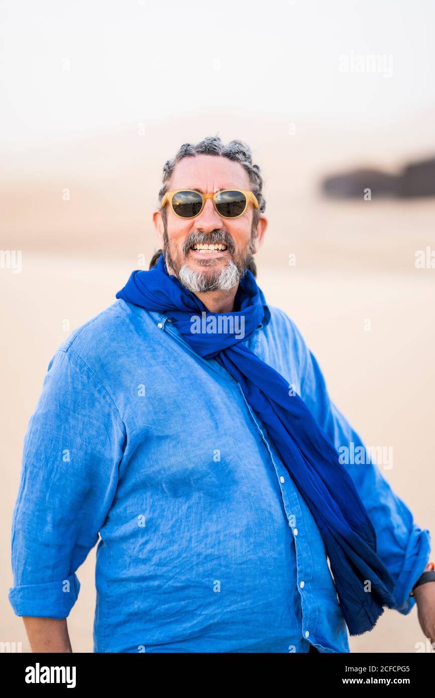 Homme à barbe mature regardant la caméra tout en marchant dans le sable Désert contre ciel gris au Maroc Banque D'Images