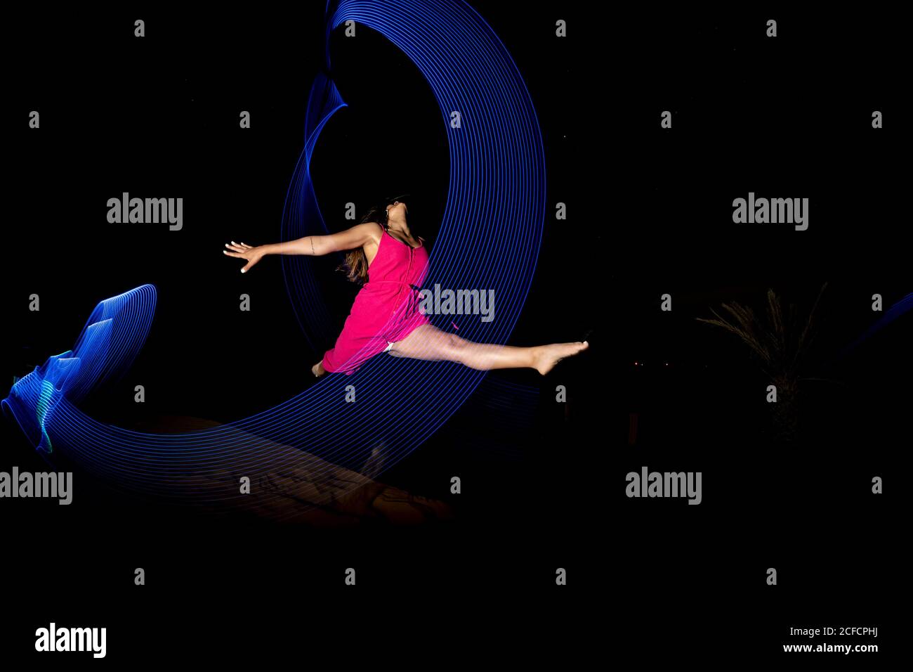 Pistes de bleu fluo curling sur la femme de danse pieds nus sur fond de  désert sombre la nuit au Maroc Photo Stock - Alamy