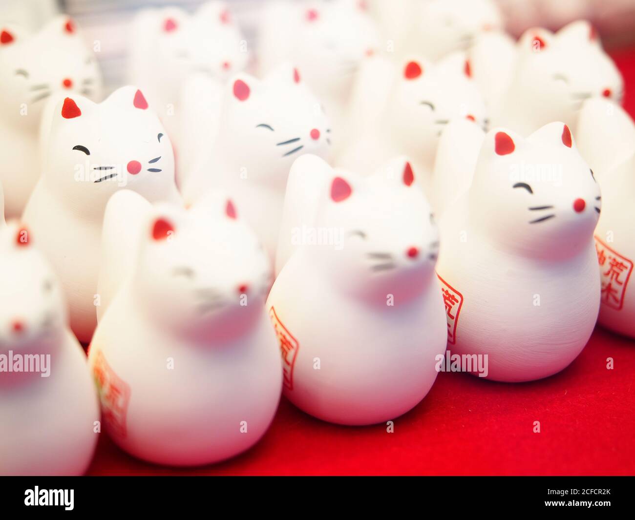 Ensemble de figurines de chat mignonnes en gros plan placé sur une cale rouge Dans le sanctuaire traditionnel de Shinto au Japon Banque D'Images