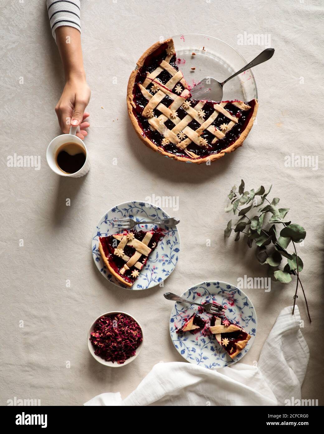 Du dessus de la crop personne assis à la table couverte avec servi café et délicieux tarte aux baies sur fond blanc Banque D'Images