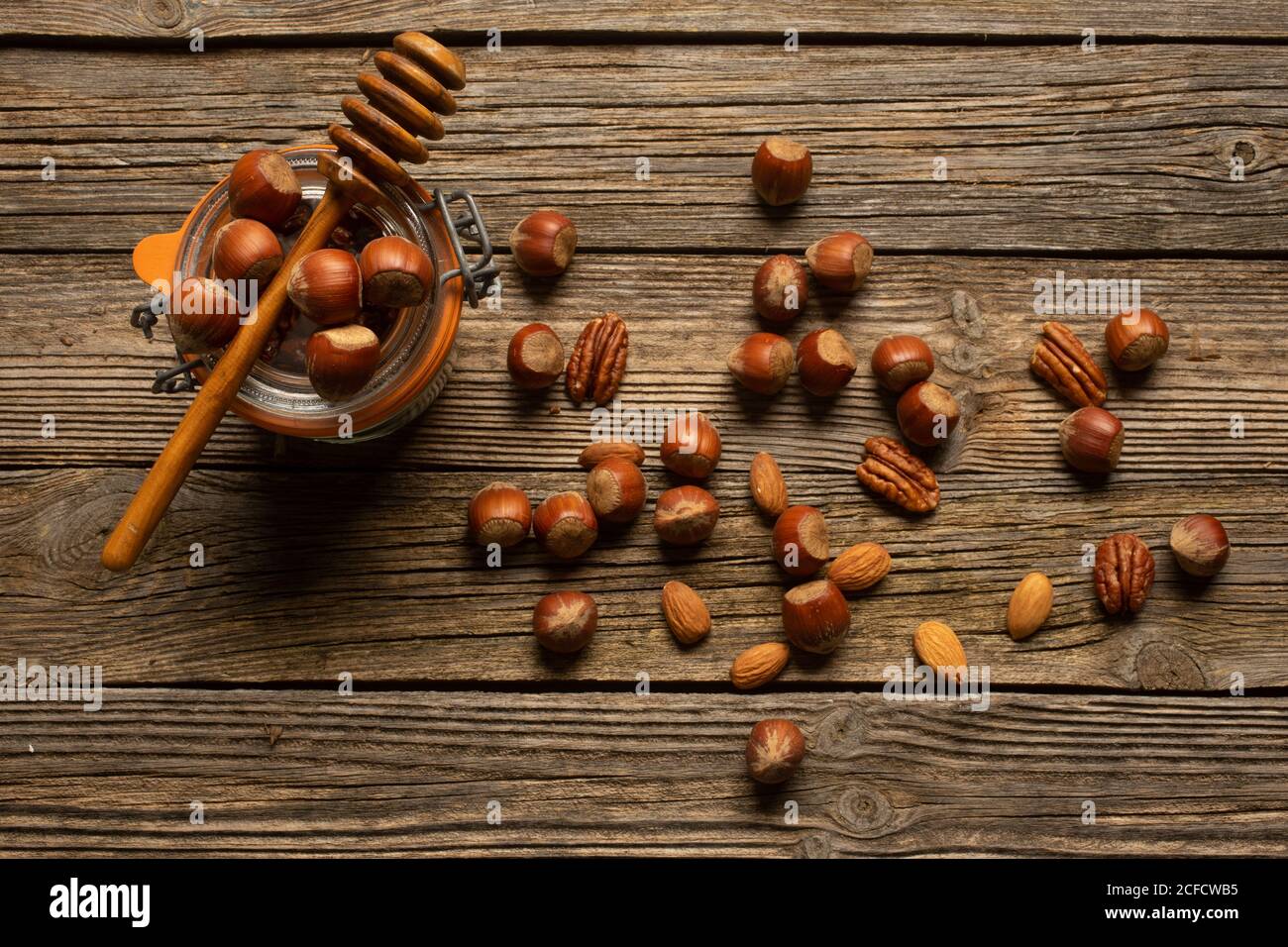 Vue de dessus de noisette avec pacane et amande près du pot et un balancier de miel en bois sur la table Banque D'Images