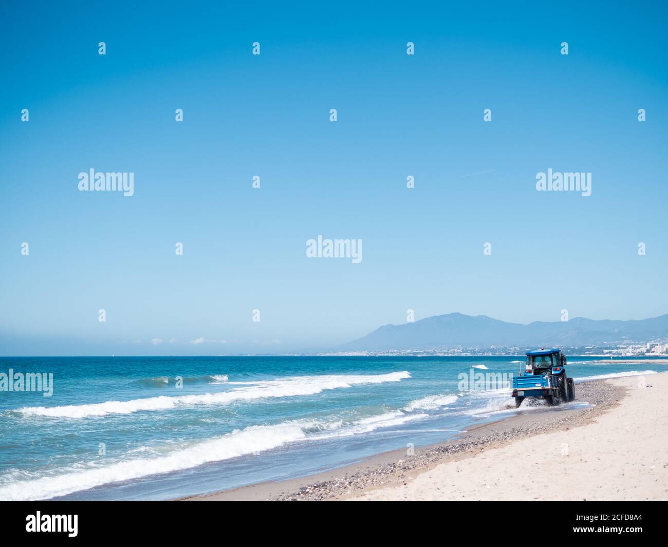 Vue pittoresque sur une mer calme et un petit tracteur le long plage de sable sur fond de ciel bleu Banque D'Images