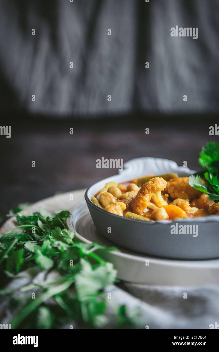 Bol avec savoureux curry de pois chiches et herbes placées près de gris serviette en tissu dans un cadre rustique Banque D'Images