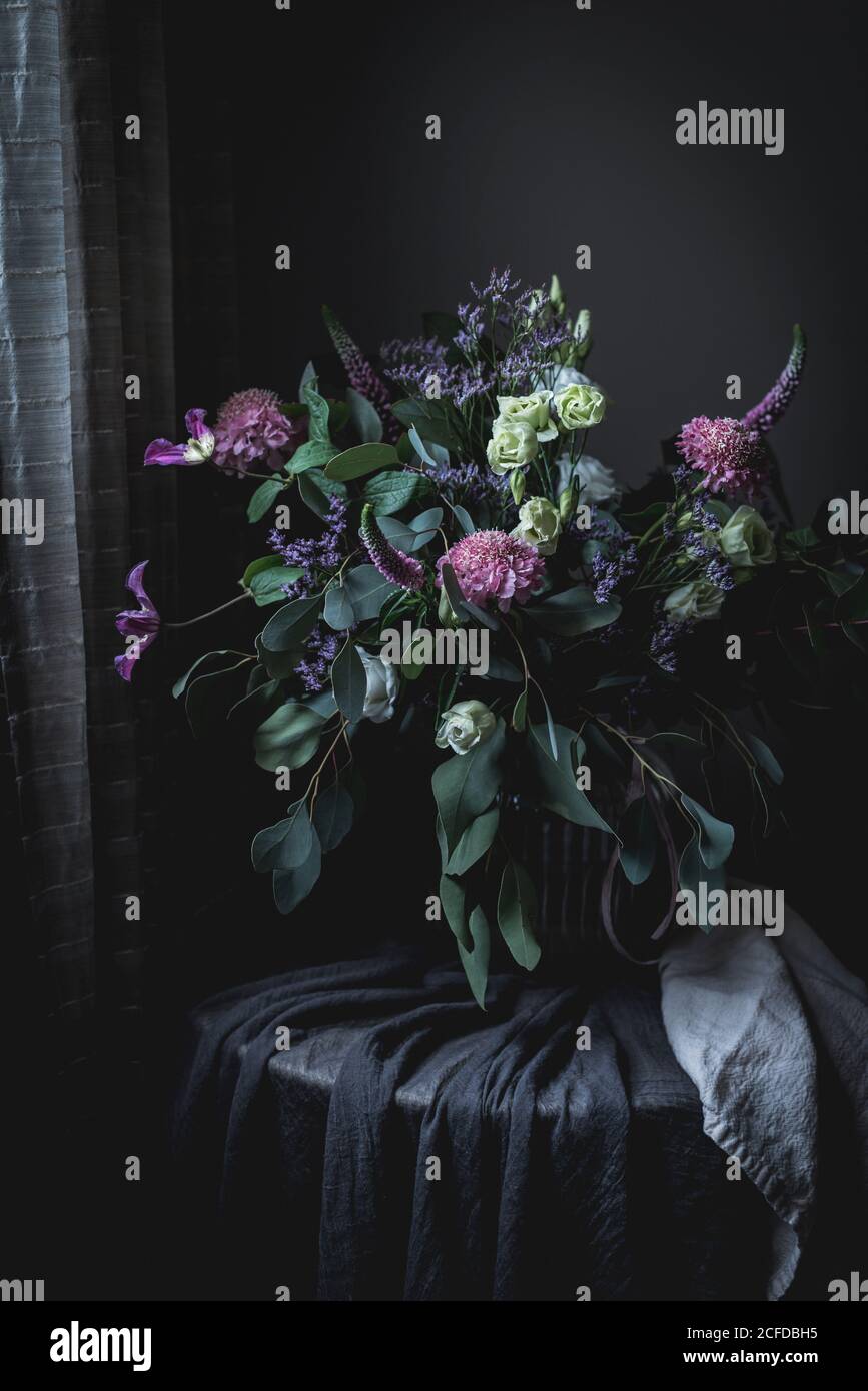 Bouquet de fleurs stupéfiant sur une table dans une obscurité chambre vintage Banque D'Images