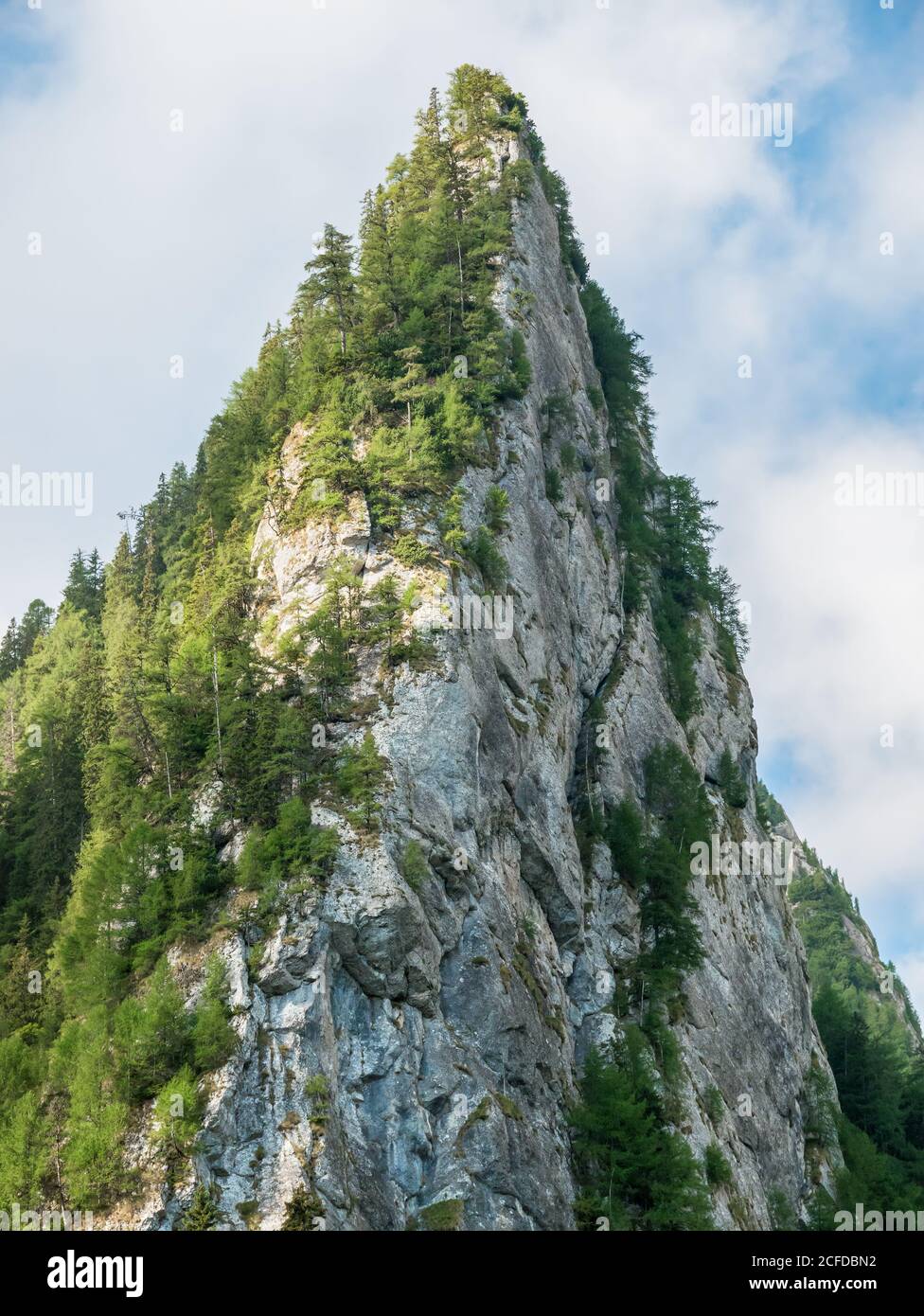 Roche en forme de pyramide vive contre ciel bleu nuageux. Détail avec un pic rocheux dans les monts Bucegi, Roumanie Banque D'Images