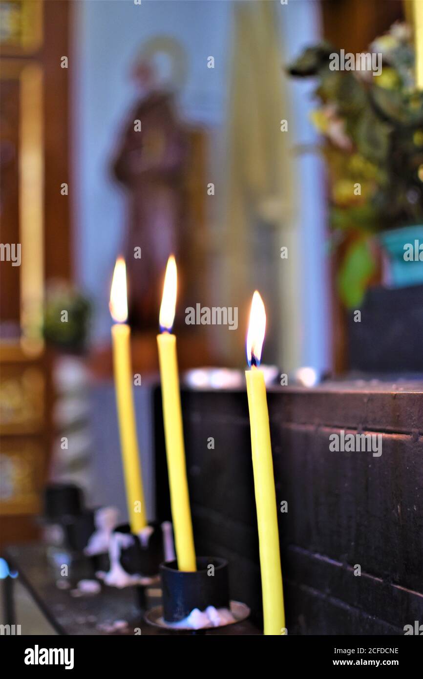 Bougies jaunes allumées sur un autel de prière à l'intérieur d'une église Banque D'Images