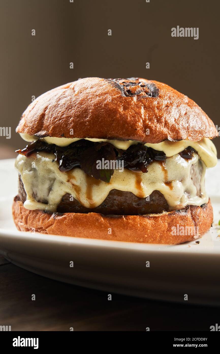 Délicieux hamburger de bœuf grillé maison avec fromage fondu servi dessus plaque sur la table Banque D'Images