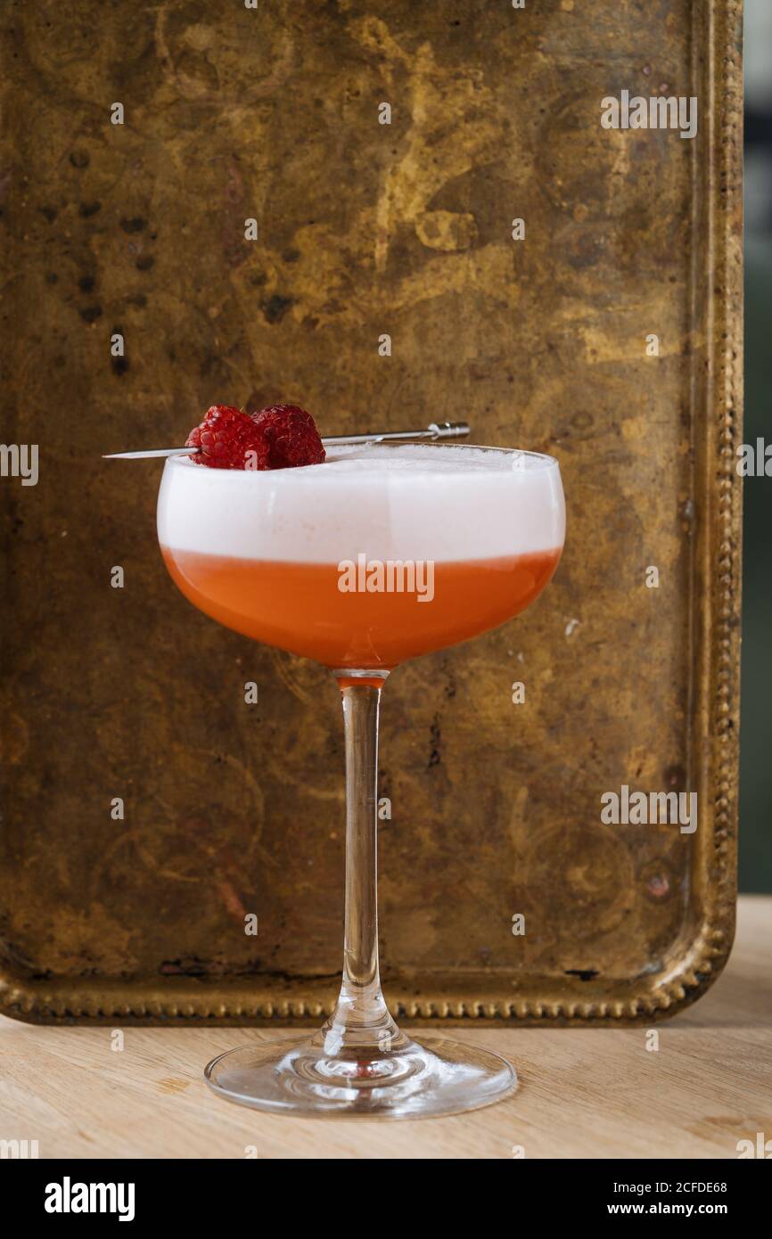 Cocktail d'alcool rouge coloré dans un élégant verre sur la table avec bar cuillère et passoire au restaurant Banque D'Images