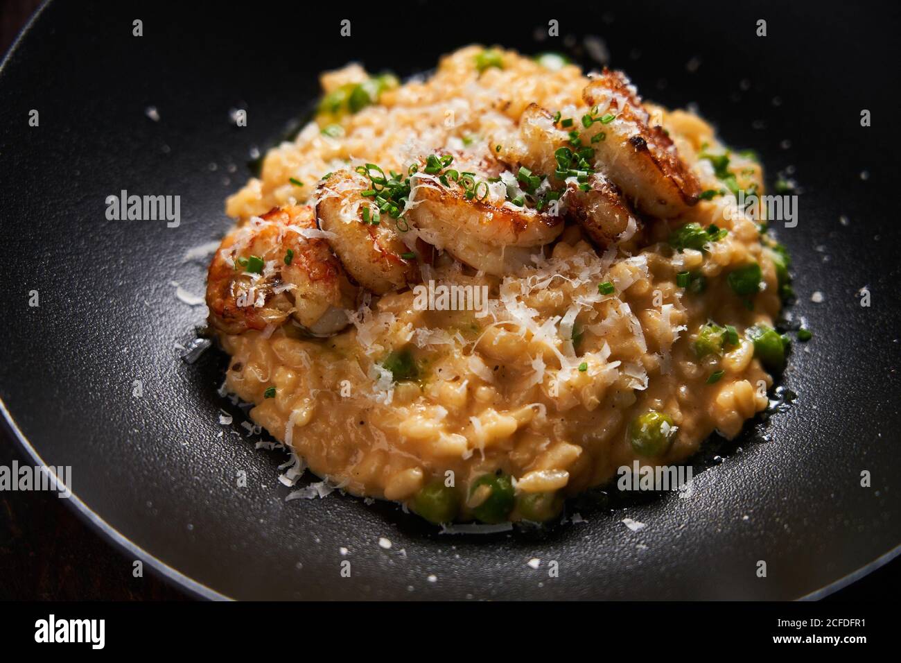 Du dessus du riz dans une sauce dorée décorée avec frit crevettes au fromage râpé et aux herbes