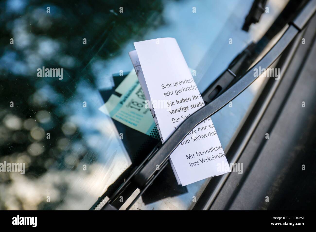 Essen, Rhénanie-du-Nord-Westphalie, Allemagne - UN billet de stationnement est bloqué sur l'essuie-glace sur le pare-brise d'une voiture dans un parking. Banque D'Images