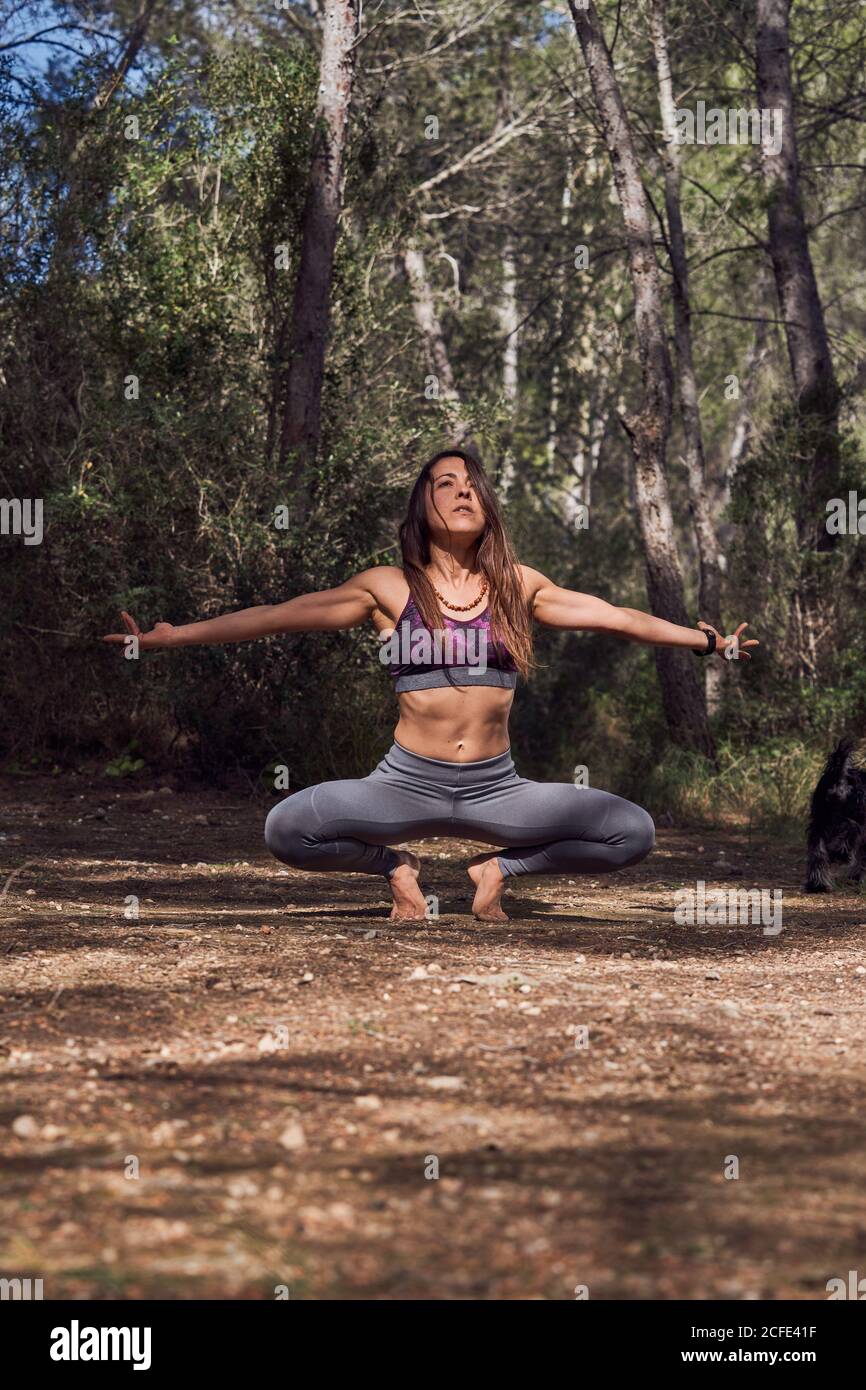 Corps complet de jeune femme en sport pratiquant le yoga classe dans la forêt printanière à l'air frais Banque D'Images
