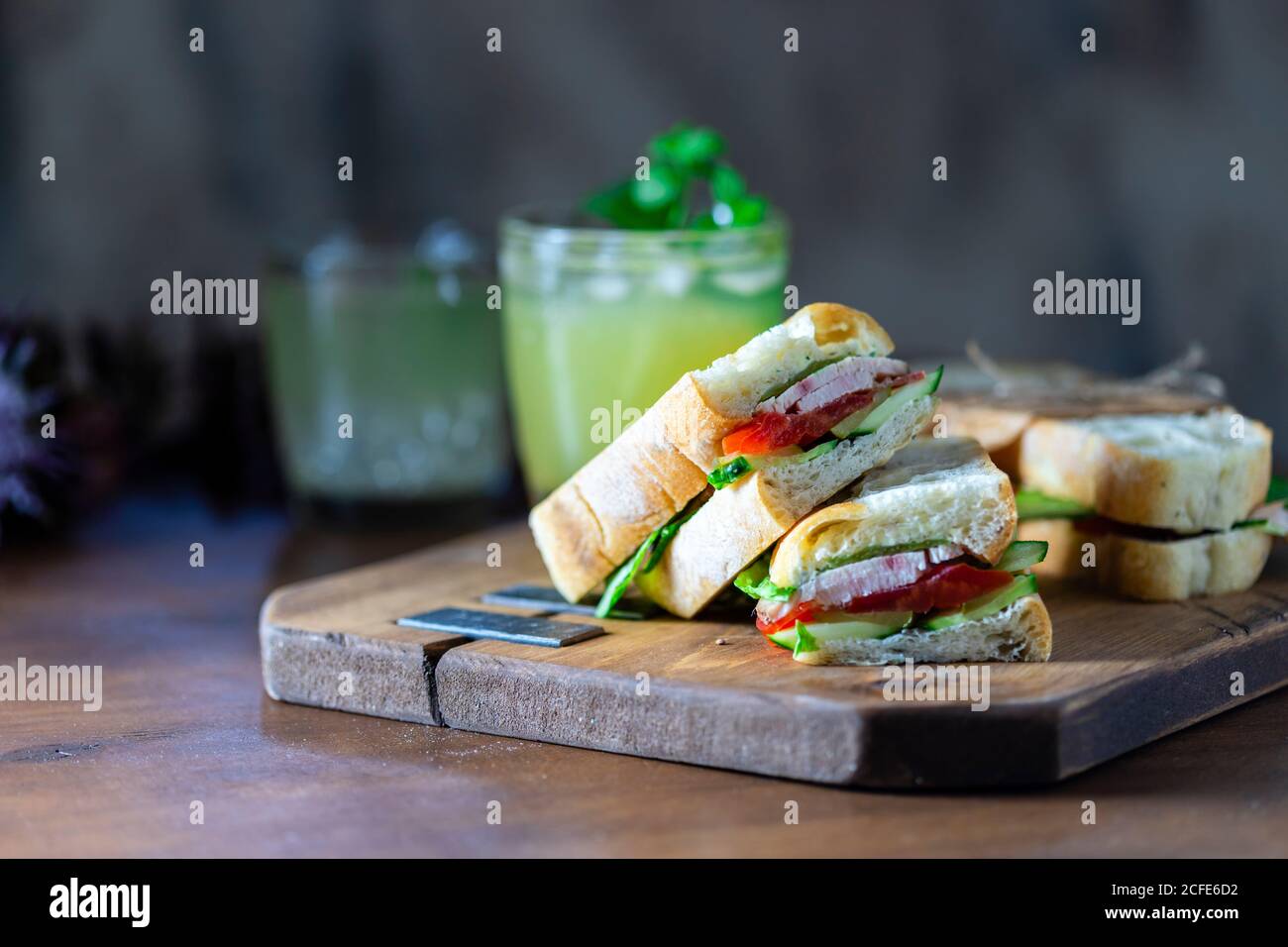 Sandwich Ciabatta avec dinde, laitue, tomates, fromage sur une planche de bois. Banque D'Images