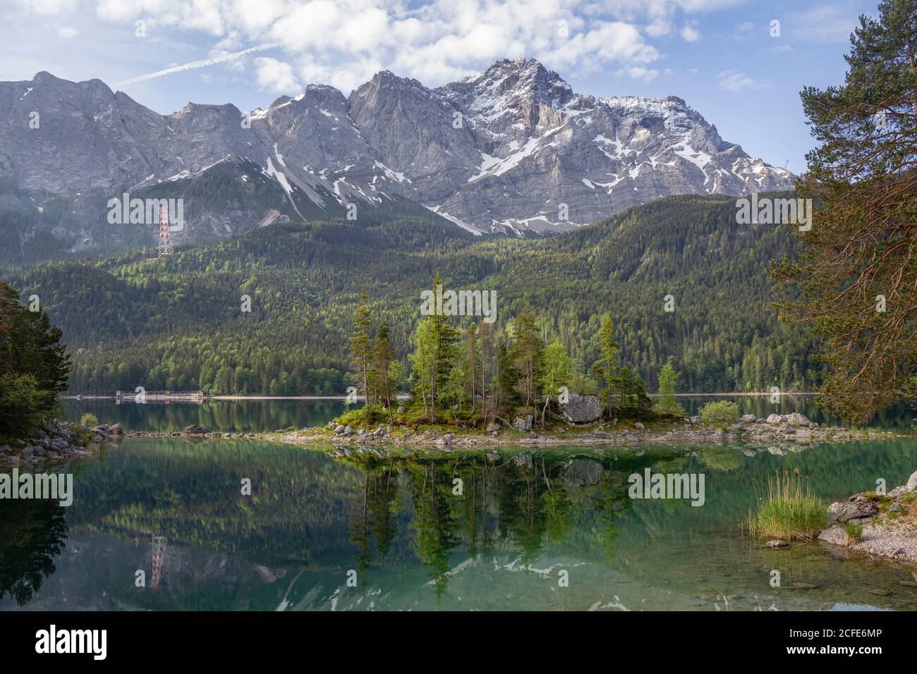 Vue sur le Braxeninsel sur l'Eibsee au printemps vers Zugspitze, la plus haute montagne d'Allemagne, eau turquoise, ciel bleu, nuages, arbres, Banque D'Images