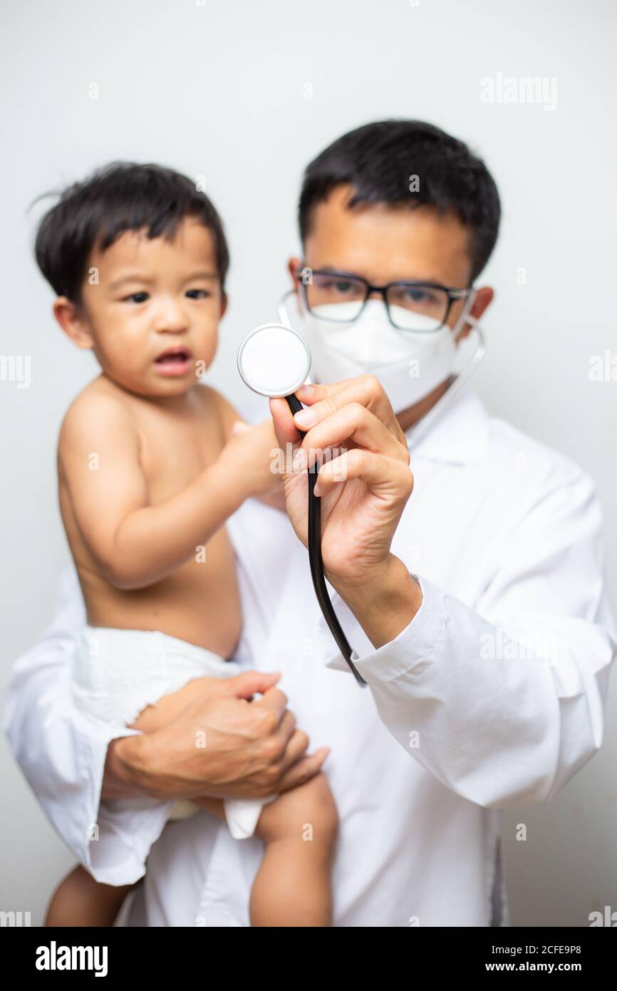 joyeux médecin asiatique masculin examinant bébé garçon avec examen  stéthoscope sur fond blanc Photo Stock - Alamy