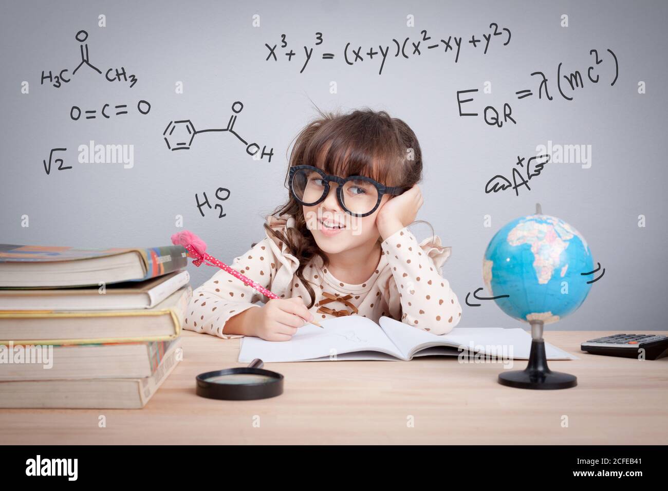 concept d'éducation. petite fille mignonne à l'école heureuse de faire des devoirs. équations mathématiques et formule chimique en arrière-plan Banque D'Images