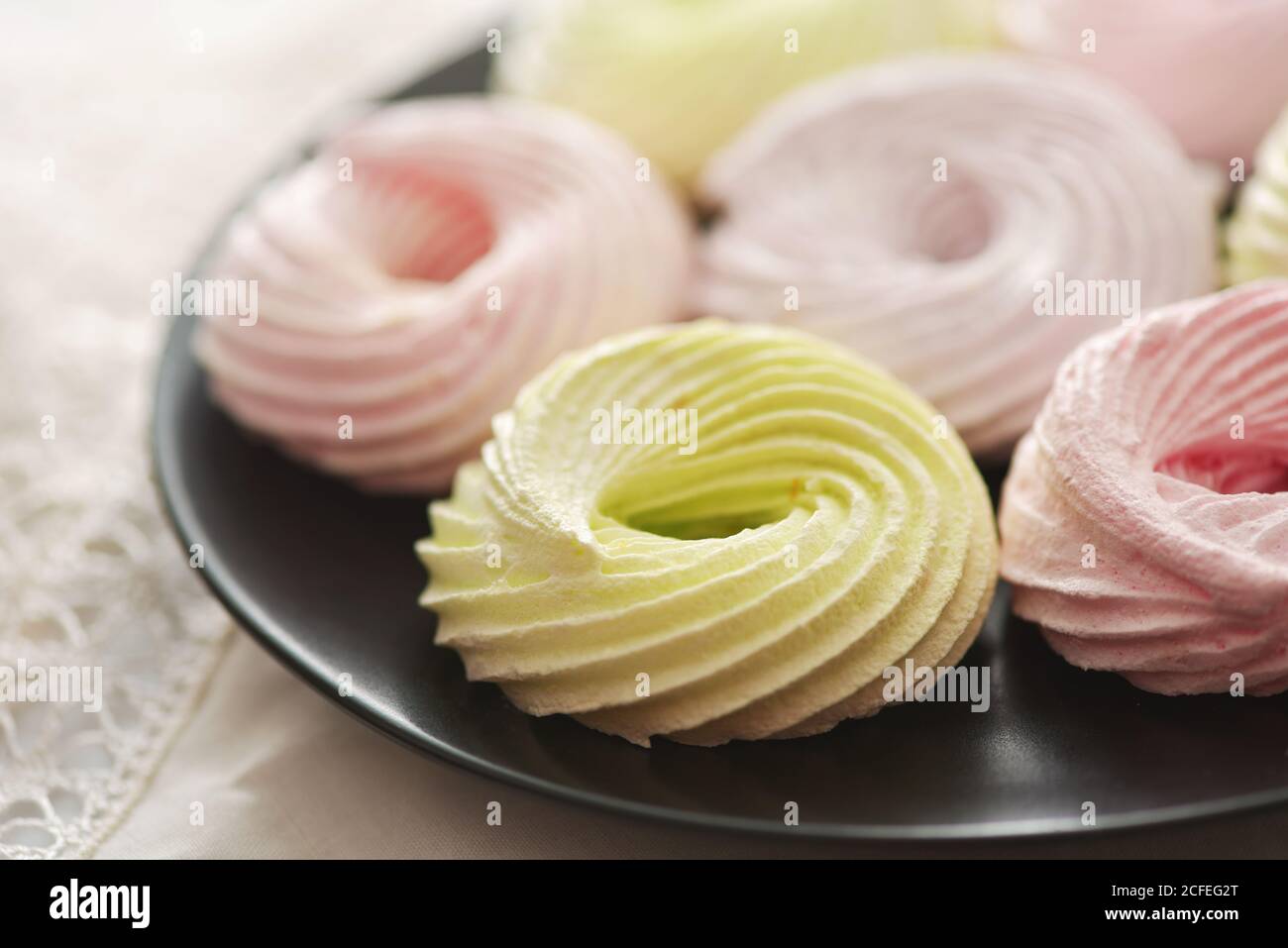 Gros plan des anneaux de meringue frais sur l'assiette noire Banque D'Images