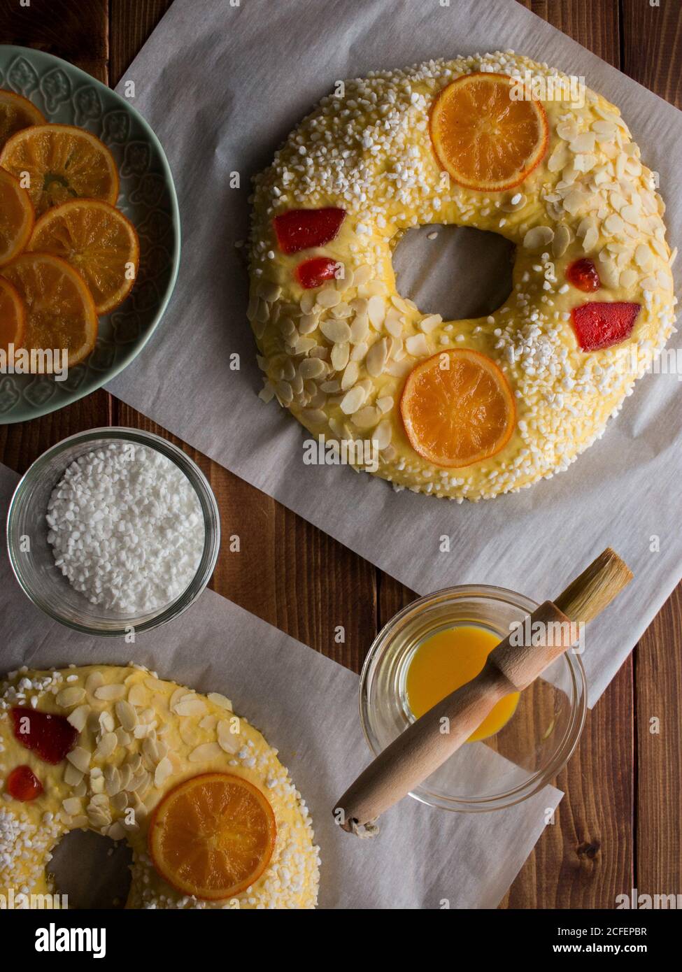 Bols avec jaune d'œuf frais et cristaux de sucre placés sur Table de bois près de délicieux Rosca de Reyes avec des fruits confits et les graines Banque D'Images