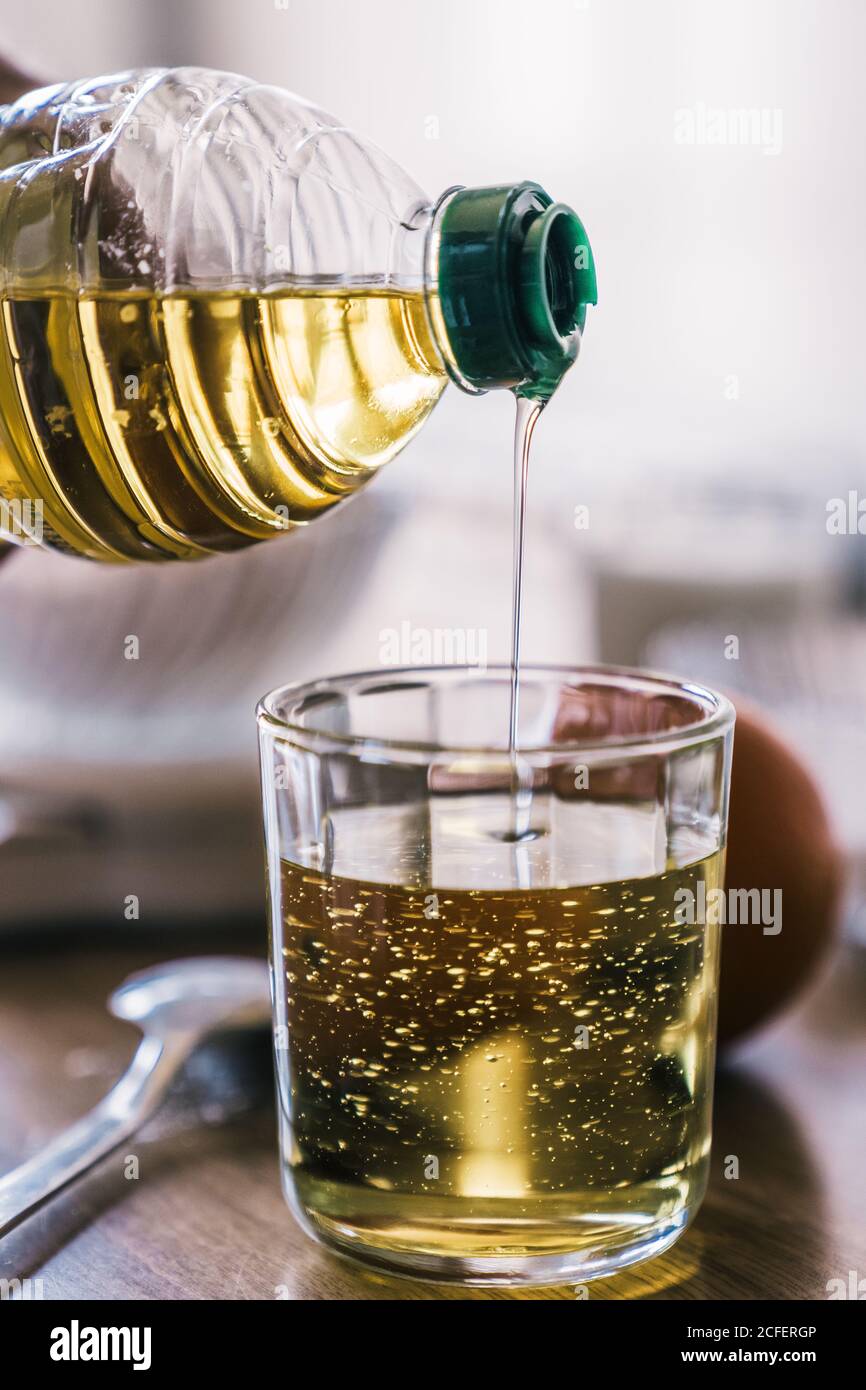 Récolte anonyme femelle versant de l'huile végétale dans le verre de mesure placé sur la table avec les ingrédients pour la recette tout en préparant la pâtisserie à accueil Banque D'Images