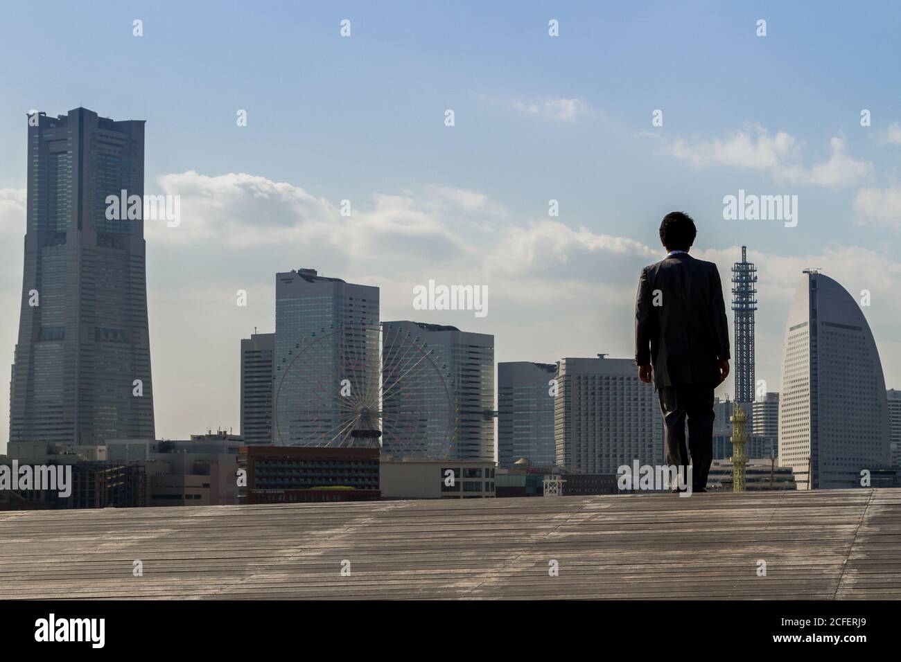 Un salaryman japonais se tient sur le quai Osanbashi en regardant l'horizon de Minato Mirai avec Landmark Tower (à gauche) Yokohama. Kanagawa Japon. Banque D'Images