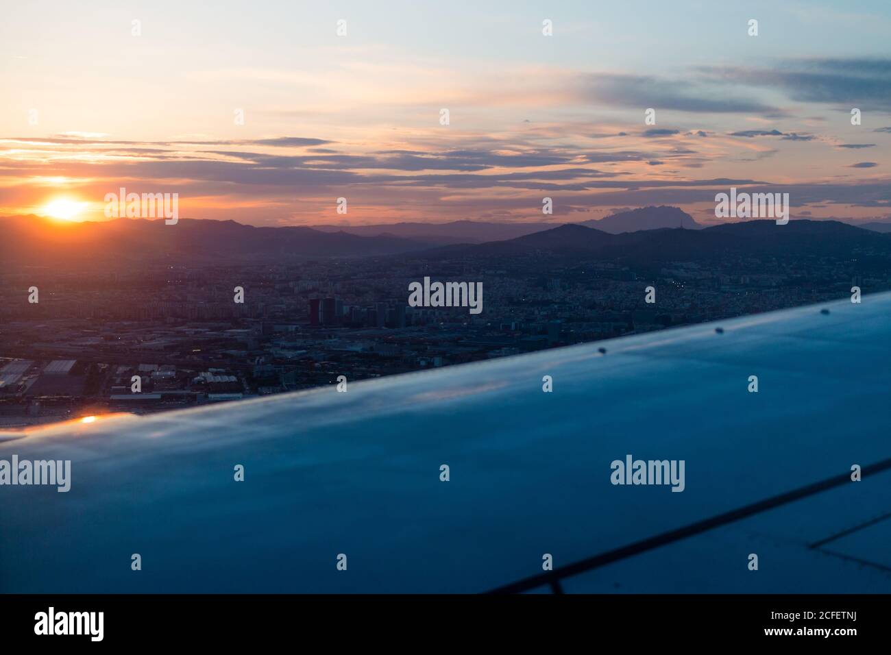 Vue depuis la fenêtre de l'aile de l'avion moderne survolant nuages denses pendant le coucher du soleil Banque D'Images