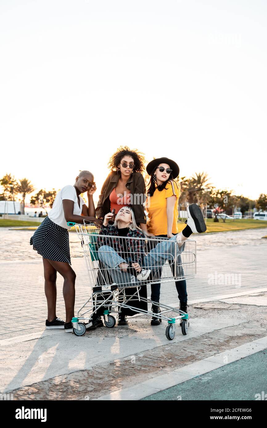 Groupe multiracial de jeunes femmes se tenant autour de chariot sur route Banque D'Images