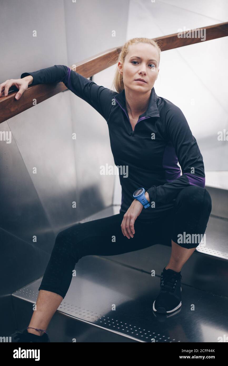 Portrait d'une jeune femme blanche blonde avec vêtements de sport à l'intérieur avec fond métallique Banque D'Images