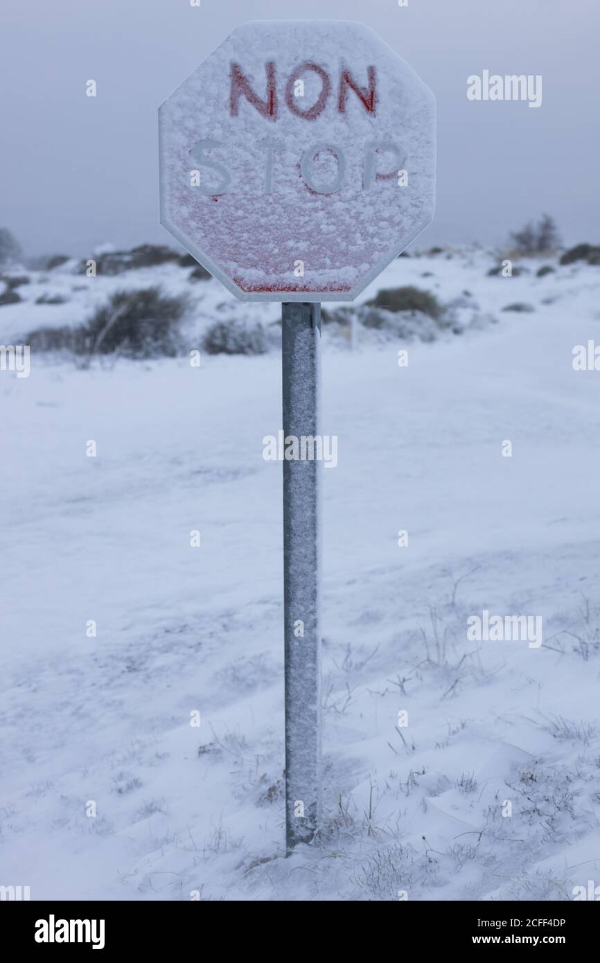 Panneau Snow Covered Stop sur terrain blanc et isolé de la colline contre le ciel gris sombre Banque D'Images